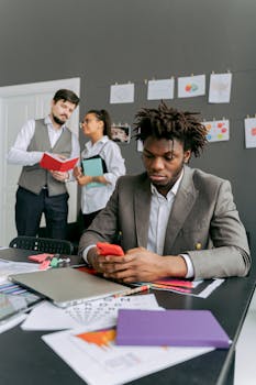 Business professionals working together in an office with smartphones and documents.