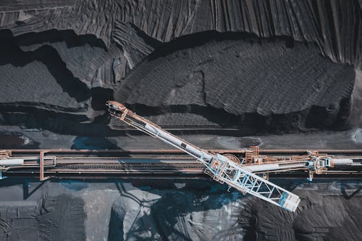 Top view of modern industrial machinery working with black natural coal in daylight